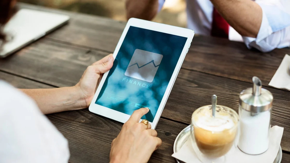 Tablet ekranında grafik inceleyen iş insanları ve masadaki kahve fincanı
